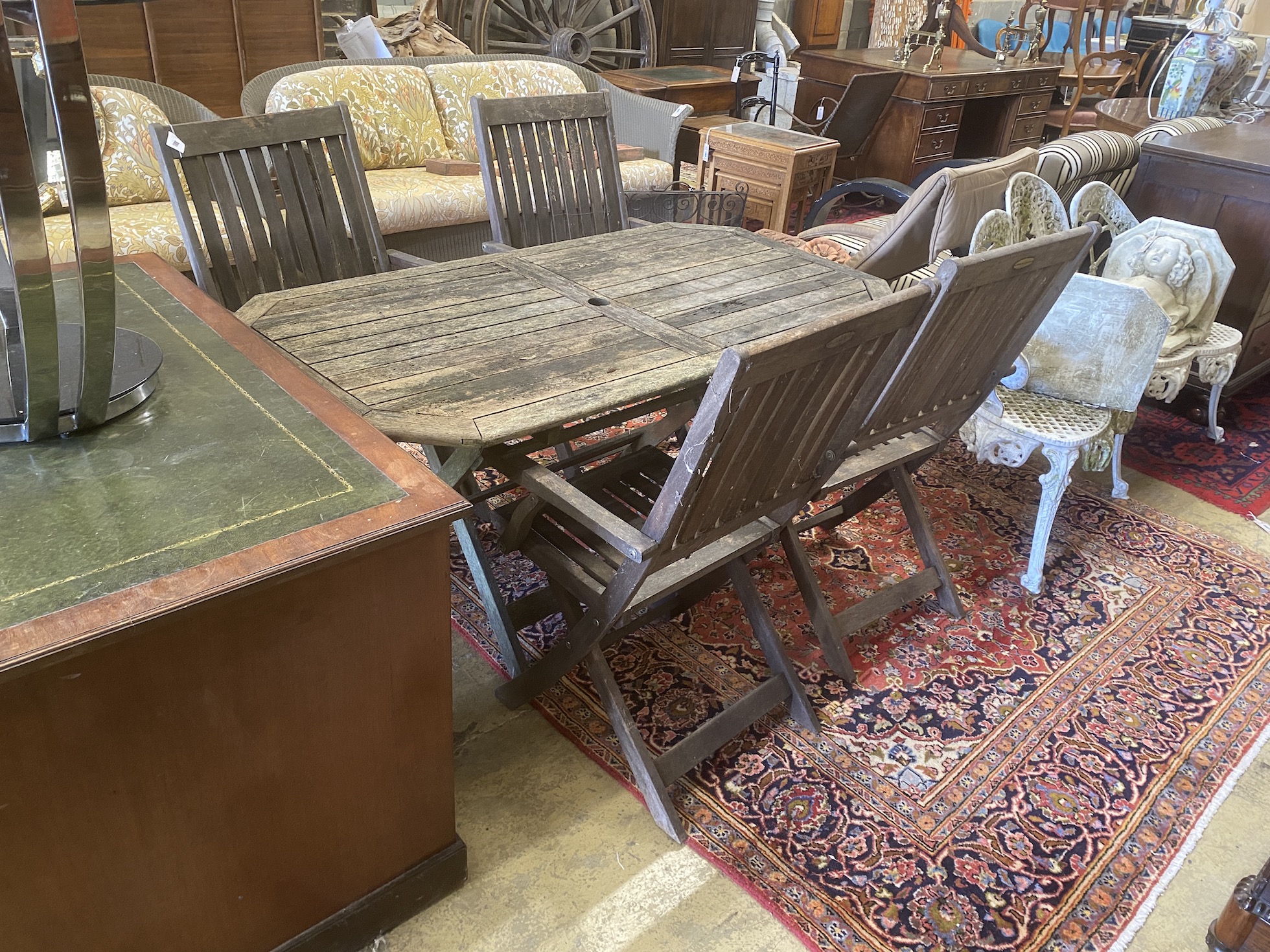 A weathered teak folding garden table, width 150cm, depth 80cm, height 70cm together with four folding teak elbow chairs
